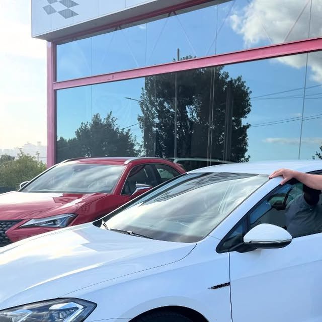 Volkswagen Golf blanco frente al concesionario, con otro coche rojo detrás