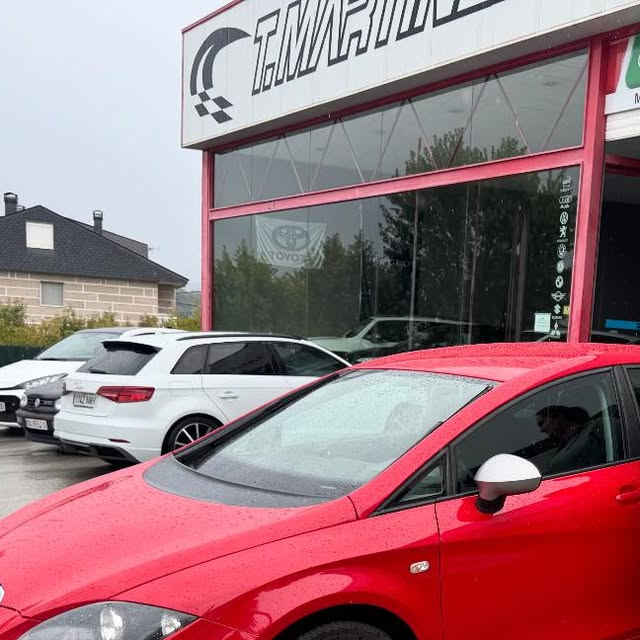 Seat León FR rojo frente al concesionario, con otros vehículos en el patio
