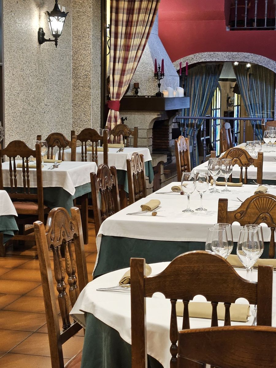 Salón principal de O Ferro Parrilla en Verín, con chimenea de piedra